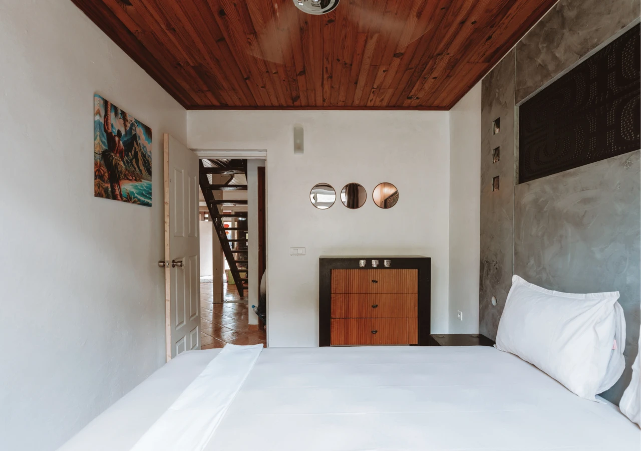 Chambre double : lit, commode et trois miroirs ronds, vue sur l'escalier